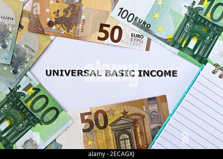 Photo TopView sur le thème du revenu de base universel. Les mots revenu de base universel sur papier, entourés de billets de banque et de bloc-notes Banque D'Images