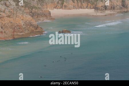 Attente sur les grands surf à Porthcurno Cove; la plage de Pedn Vounder au loin. Pedn Vounder est une plage naturiste non officielle. Penwith Peninsula, Cornwall. Banque D'Images