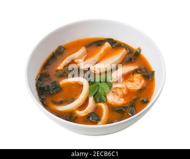 Délicieuse soupe thaï tom yum avec fruits de mer et poulet. Isolé sur un fond blanc. Banque D'Images