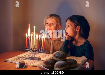 Filles amis éclairant des bougies sur la menorah pour l'hiver traditionnel juif Hanukkah vacances à la maison. Les enfants célèbrent le festival des lumières de Chanukah. Banque D'Images