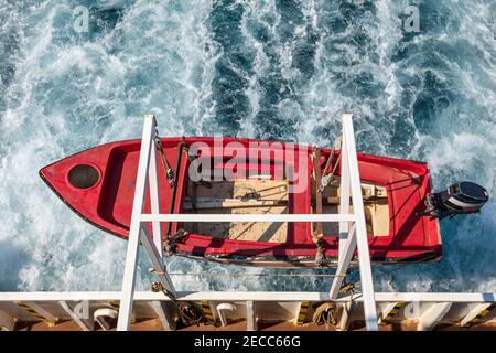 Canot de sauvetage rouge suspendu au-dessus de la mer sur le côté d'un ferry. Banque D'Images