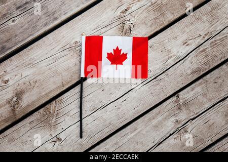 Drapeau canadien rouge avec feuille d'érable rouge sur fond de planches en bois à l'extérieur. Symbole du drapeau canadien lors de la célébration nationale de la fête du Canada le 1er juillet. Banque D'Images