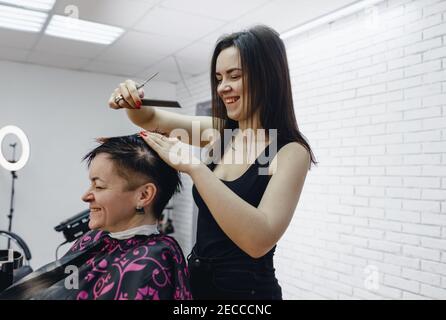 un coiffeur féminin coupe les extrémités des cheveux des femmes dans un salon de beauté, gros plan Banque D'Images