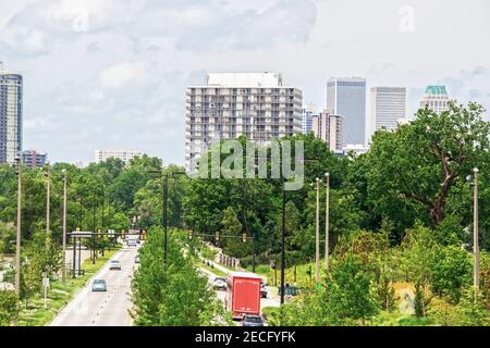 Autoroute divisée avec beaucoup de végétation luxuriante et feu vert Avec des voitures, des camions et des piétons menant au centre-ville de Tulsa Oklahoma États-Unis Banque D'Images