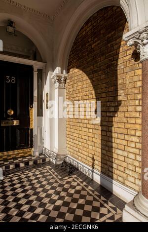 Entrée très ornée dans un immeuble d'appartements à Kensington, Londres, arches décoratives, mur de briques, ombres profondes et carreaux à carreaux Banque D'Images