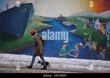 Portland, États-Unis. 13 février 2021. Un homme marche son chien devant une fresque de la rivière Willamette sur North Mississippi Avenue à Portland, en Oregon, le 13 février 2021, après deux nuits de temps d'hiver qui ont entraîné une chute de neige importante dans la région. (Photo par Alex Milan Tracy/Sipa USA) crédit: SIPA USA/Alay Live News Banque D'Images