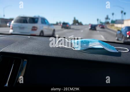 Un masque se trouve sur le tableau de bord d'une voiture lorsqu'elle navigue sur l'autoroute 5 en direction de Los Angeles. Banque D'Images