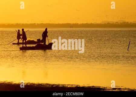 Vue sur la silhouette des pêcheurs avec leurs bateaux dans un lac au coucher du soleil. Mise au point sélective Banque D'Images