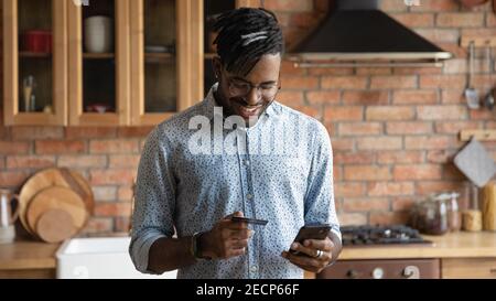 Gros plan sourire Africain américain homme payant carte de crédit en ligne Banque D'Images