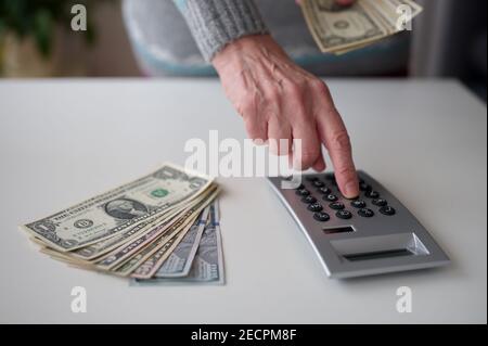 Photo rognée de la main tenant des billets en dollars et calculant Banque D'Images