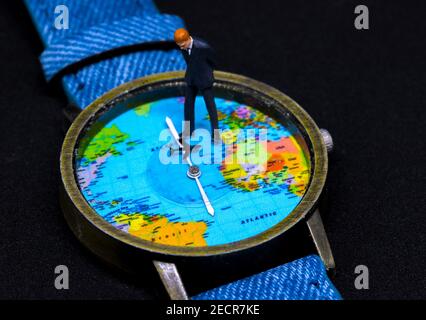 Homme d'affaires, figurine sur la montre. Horloge cartographique mondiale. Concept commercial mondial. Homme d'affaires macro photo. Décision de planification stratégique de la société mondiale. G Banque D'Images