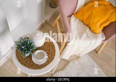 Elégant et élégant salon de composition écologique avec table de petit-déjeuner blanc café tasse théière fausse cheminée fleurs séchées plantes pampas herbe rose poudreuse fauteuil, couverture et oreiller. Décoration moderne. Banque D'Images