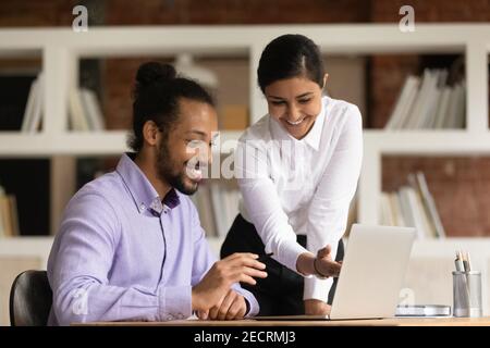 Des collègues heureux et variés coopèrent sur ordinateur au bureau Banque D'Images
