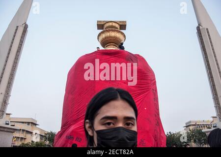 Un manifestant pro-démocratie portant un masque facial se trouve devant le Monument de la démocratie pendant la manifestation.des manifestants pro-démocratie se sont rassemblés au Monument de la démocratie. Ils ont enveloppé le Monument d'un immense tissu rouge et ont défilé jusqu'au Sanctuaire du pilier de la ville de Bangkok près du Grand Palais Royal demandant la réforme de la monarchie et d'abolir la loi de la majesté lese (article 112 du Code criminel thaïlandais) et la libération de 4 activistes (Somyot Pruksakasemsuk, Patiwat Saraiyam, Parit 'Penguin' Chivarak et Anon Nampa) qui ont été arrêtés par la loi sur la majesté lese (article 112). Banque D'Images