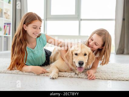 Les enfants qui pamblent l'Golden Retriever à la maison Banque D'Images