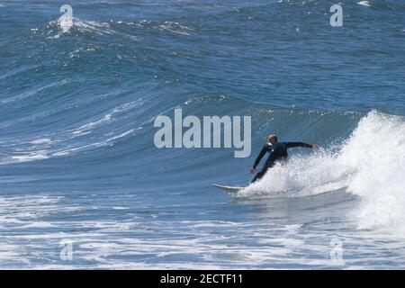 Un surfeur descend une vague sur une plage de manière sportive Au Portugal sur l'océan Atlantique Banque D'Images