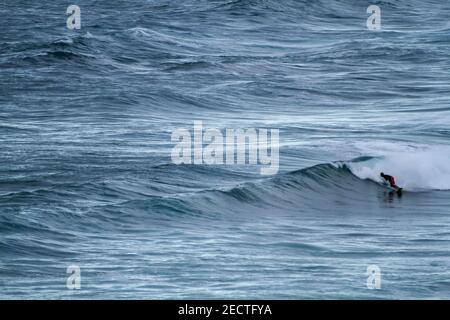 Un surfeur descend une vague sur une plage de manière sportive Au Portugal sur l'océan Atlantique Banque D'Images