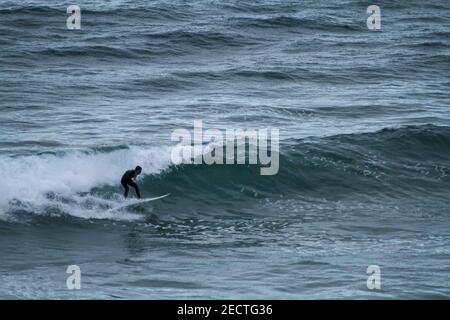 Un surfeur descend une vague sur une plage de manière sportive Au Portugal sur l'océan Atlantique Banque D'Images