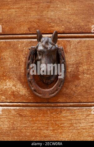 Ancien knocker de porte en forme de cheval italien sur fond de porte marron en bois. Banque D'Images