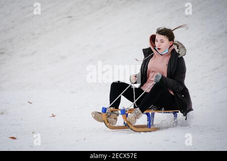 Varsovie. 13 février 2021. Une fille descend une colline sur un traîneau à Varsovie, en Pologne, le 13 février 2021. Les prix et les ventes de traîneau en Pologne ont considérablement augmenté cette année en raison de la chute de neige importante qui n'a pas été observée depuis des années, ont rapporté les médias locaux. Credit: Jaap Arriens/Xinhua/Alamy Live News Banque D'Images