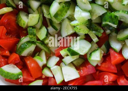 Légumes frais sains, petites tranches de concombres verts et tomates rouges pour la salade d'été, ingrédients pour la salade. Banque D'Images