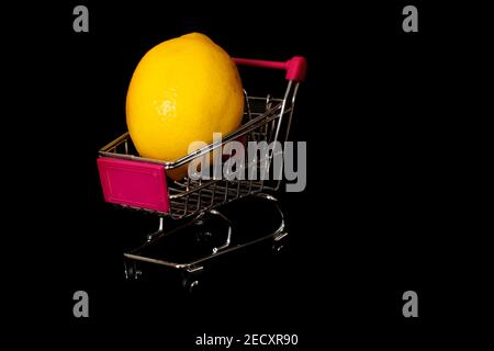 Citron frais bio dans un mini chariot ou un chariot. Isolé sur fond noir. Espace pour le texte. Banque D'Images