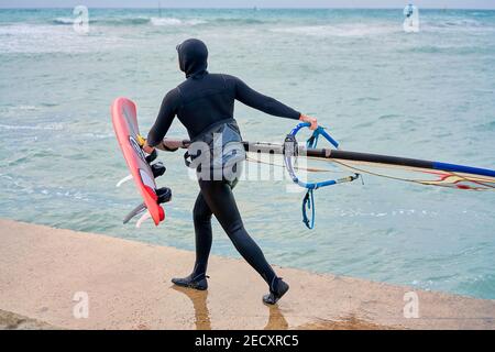 Hiver planche à voile, l'homme dans la combinaison de windsurfs en hiver, dans le fond lointain vous pouvez voir le bar de glace Banque D'Images