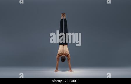 Le yoga masculin se divise sur les mains, vue arrière Banque D'Images