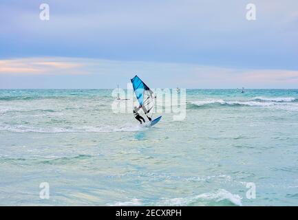 Hiver planche à voile, l'homme dans la combinaison de windsurfs en hiver, dans le fond lointain vous pouvez voir le bar de glace Banque D'Images