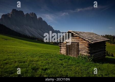 Clair de lune sur la montagne Odle groupe. Chalet en bois, prairies alpines. Nuit paysage de montagne. Les Dolomites de Funes valley. Alpes italiennes. L'Europe. Banque D'Images