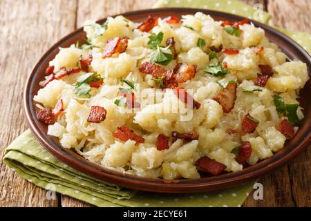 Boulettes de pommes de terre halusky, râpées de pommes de terre, avec choucroute et bacon, dans l'assiette de la table. Horizontal Banque D'Images