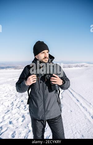 Portrait d'un beau photographe dans la neige tout en marchant à la recherche de l'aventure. Banque D'Images