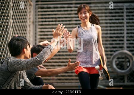 jeune femme adulte asiatique skateboarder donnant un groupe de jeunes hommes hi-cinq, se concentrer sur la main Banque D'Images