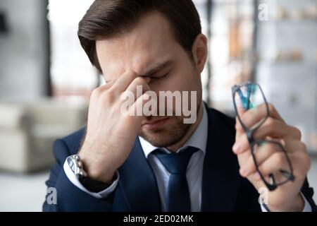 Un employé de sexe masculin épuisé souffre de maux de tête sur le lieu de travail Banque D'Images