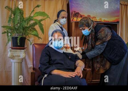 Broumana, Liban. 14 février 2021. Une nonne reçoit une dose du vaccin du coronavirus Pfizer/BioNTech (COVID-19) dans une maison âgée du village de Broumana à l'est de Beyrouth. Le Liban lance une campagne de vaccination après avoir reçu hier, samedi, le premier lot de vaccins. Credit: Marwan Naamani/dpa/Alamy Live News Banque D'Images