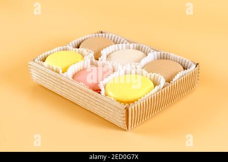 Emballage de macarons colorés dans une boîte en carton sur fond beige Banque D'Images