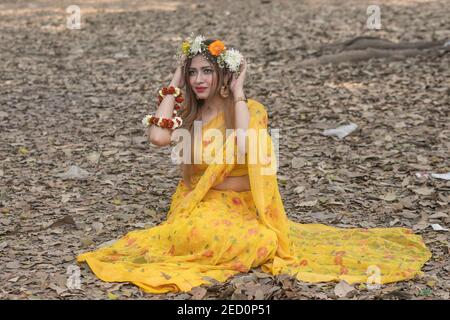 Une femme pose pour une photo portant un saris jaune et une couronne de fleur pour célébrer le Pohela Falgun, le premier jour du printemps à Dhaka.Pohela Falgun également connu comme le premier jour du printemps du mois Bengali Falgun, est une fête célébrée au Bangladesh. Des centaines de personnes se sont rassemblées sur le campus de l'Université de Dhaka pour accueillir la première journée de Basanta Utsab (festival de printemps) à Dhaka. Banque D'Images