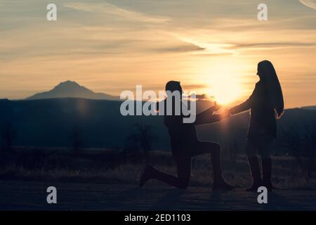 Proposition de mariage d'un jeune couple en silhouette pendant le coucher du soleil en Cappadoce. Le soleil se lève à côté de l'anneau de diamant Banque D'Images
