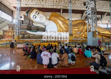 Pèlerins priant devant le bouddha couché, Temple Shwethalyaung, Bago, Myanmar Banque D'Images