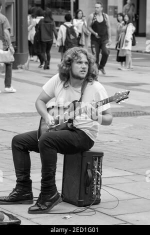 Au milieu du centre-ville de York, un homme aux cheveux longs et bouclés était assis sur un petit haut-parleur et jouait une guitare électrique., North Yorkshire, Royaume-Uni. Banque D'Images