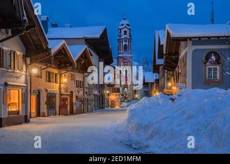 Zone piétonne au centre avec maisons typiques et église paroissiale au crépuscule, Mittenwald, Werdenfelser Land, haute-Bavière, Bavière, Allemagne Banque D'Images