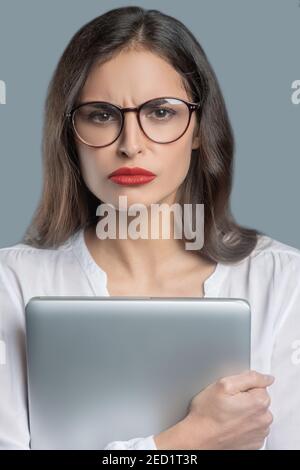 Jeune femme sérieuse avec regard de poupe dans les lunettes Banque D'Images