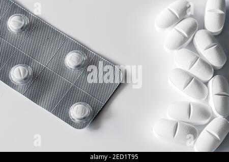 Gros plan de la pile de pilules et de la plaquette thermoformée avec tablettes blanches placées sur fond blanc Banque D'Images