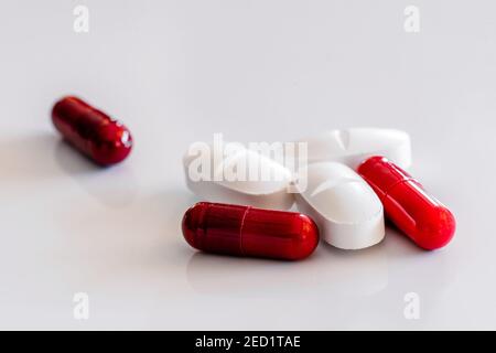Assortiment de pilules et capsules colorées et blanches placées sur blanc tableau Banque D'Images