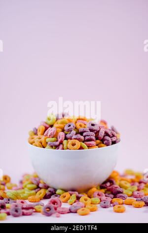 De dessus pile d'anneaux de céréales colorés dans un bol préparé pour le petit déjeuner placé sur table violette dans le studio Banque D'Images