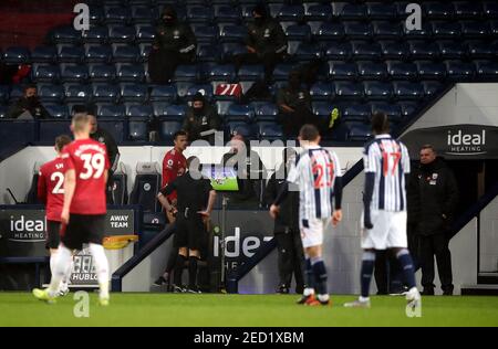 L'arbitre Craig Pawson consulte le contrôleur VAR du terrain avant de renverser une décision de pénalité donnée à Manchester United lors du match de la Premier League aux Hawthorns, West Bromwich. Date de la photo: Dimanche 14 février 2021. Banque D'Images