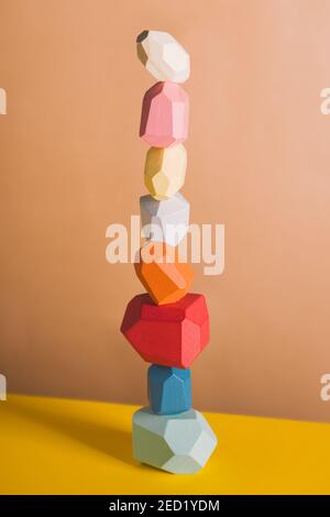 Blocs en bois de formes de pierres précieuses de différentes couleurs empilées sur fond beige en studio Banque D'Images