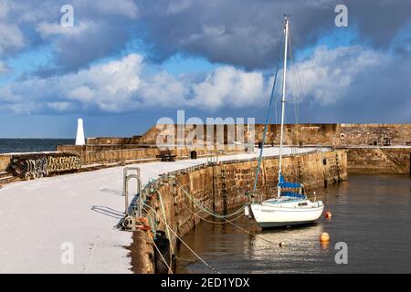 CULLEN BAY MORAY FIRTH SCOTLAND HARBOUR OU MUR DE JETÉE COUVERT DANS LA NEIGE AVEC YACHT AMARRÉ Banque D'Images