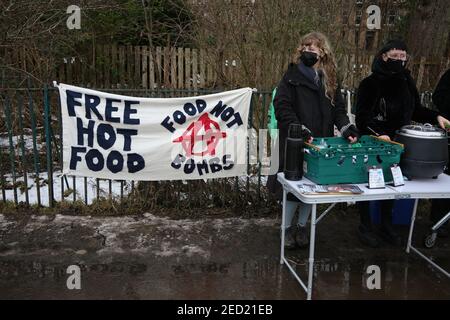Glasgow, Royaume-Uni, le 14 février 2021. Trois volontaires pour l'organisation « Food Not Bombs (Glasgow) », donnent de la soupe chaude et des haggis végétaliens, dans Queen's Park. C'est le 4ème week-end de la stalle fournissant de la nourriture, donnée par des entreprises locales, à quiconque en fait la demande, et des vêtements à ceux qui en ont besoin, dans le sud de la ville pendant la pandémie de santé actuelle du coronavirus Covid-19. Crédit photo: Jeremy Sutton-Hibbert/ Alamy Live News. Banque D'Images