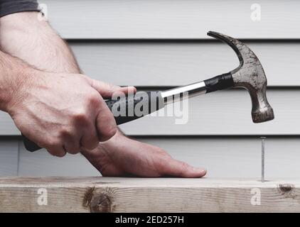 Gros plan de l'homme martelant l'ongle dans la planche Banque D'Images